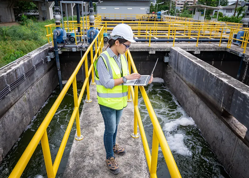 Worker in water sanitization plant on laptop